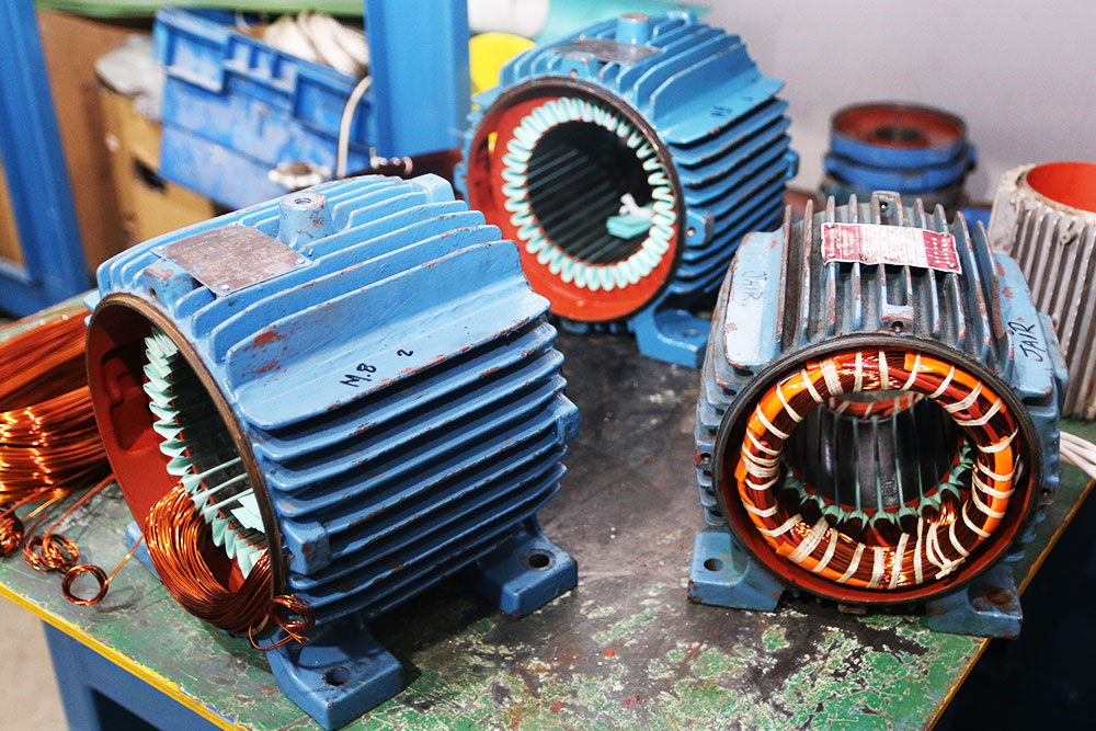 Motores elétricos abertos em bancada durante rebobinamento